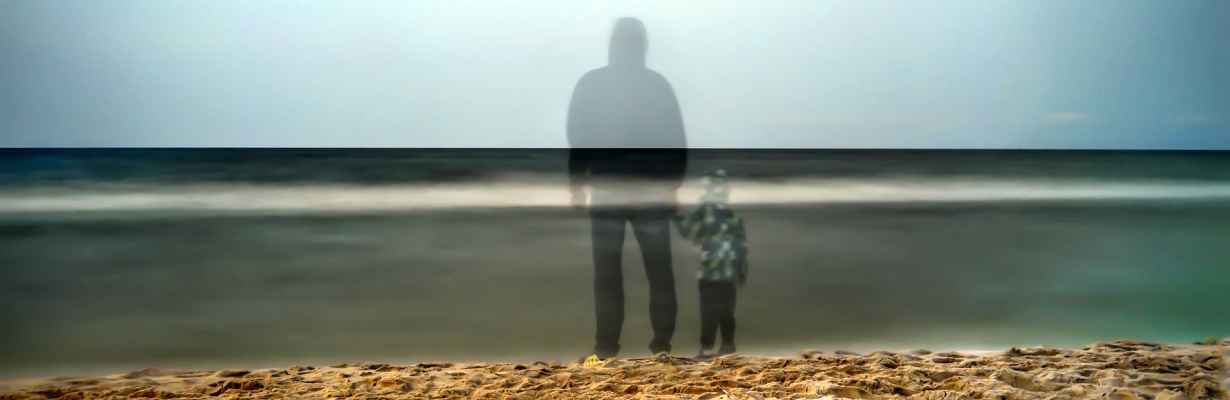Shadow silhouettes of father and son next to ocean